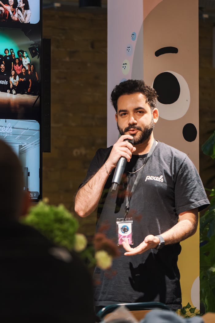 Man delivering a speech with a microphone at an indoor event. Engaged audience and warm ambiance.